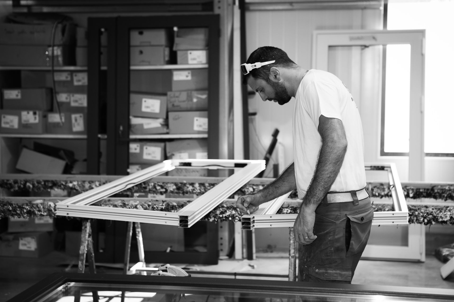 Un ouvrier se concentre sur l'assemblage d'une structure métallique sur un établi dans un atelier industriel lumineux et bien organisé.