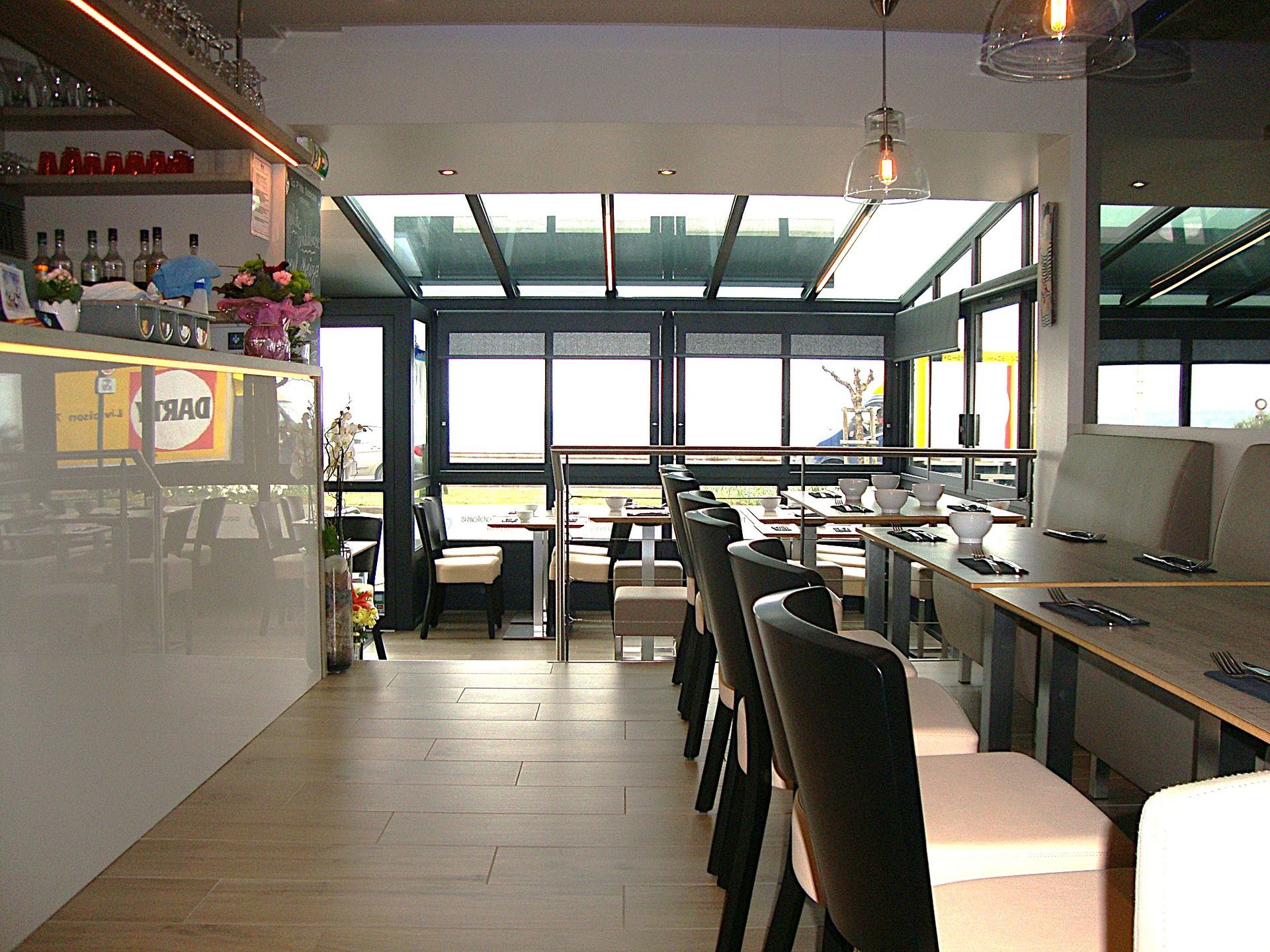 Intérieur de café moderne avec tabourets de bar, places assises au comptoir et grandes fenêtres à l'arrière