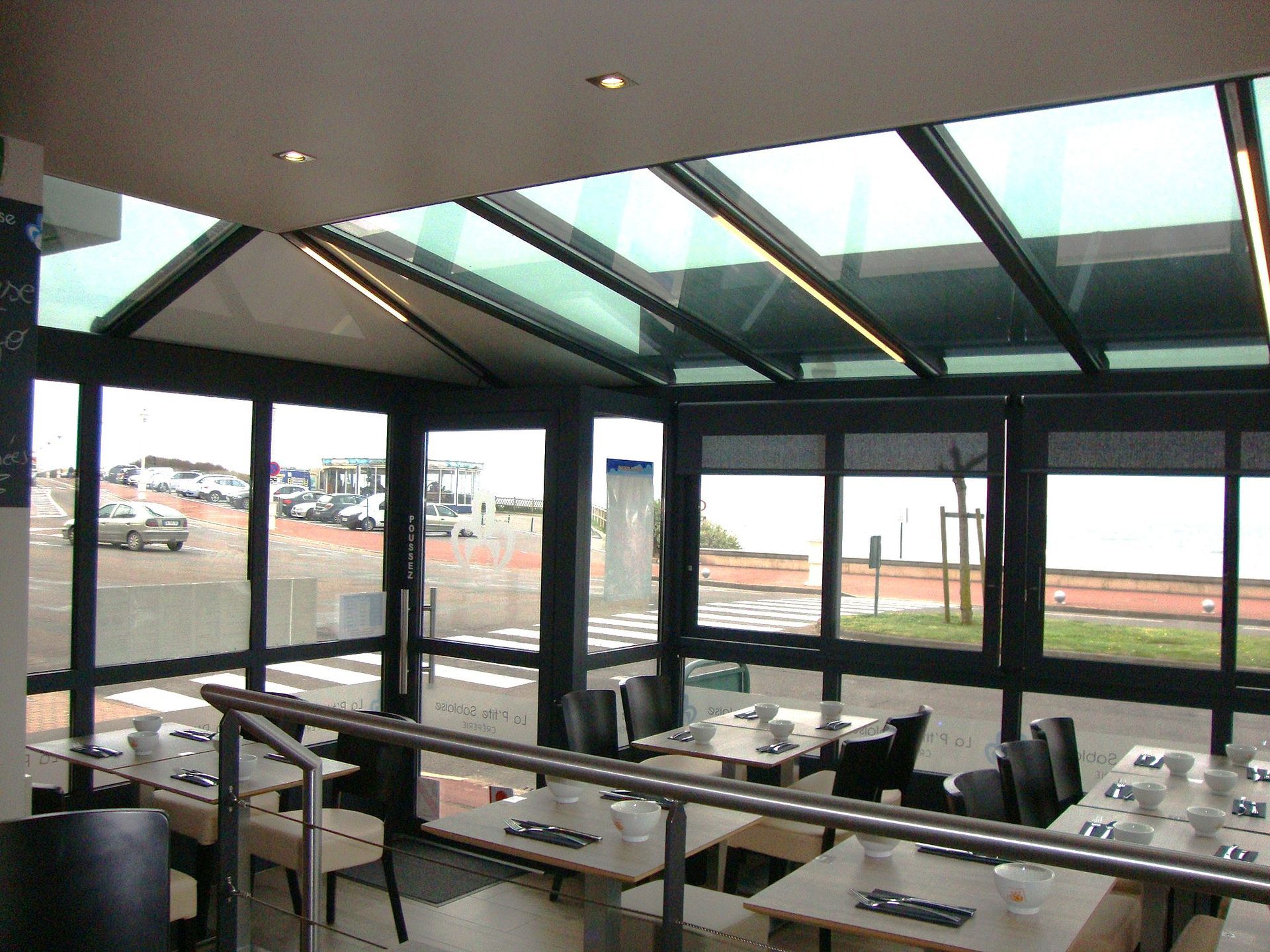 Salle à manger moderne aux parois de verre, avec tables et chaises donnant sur une piste d'aéroport