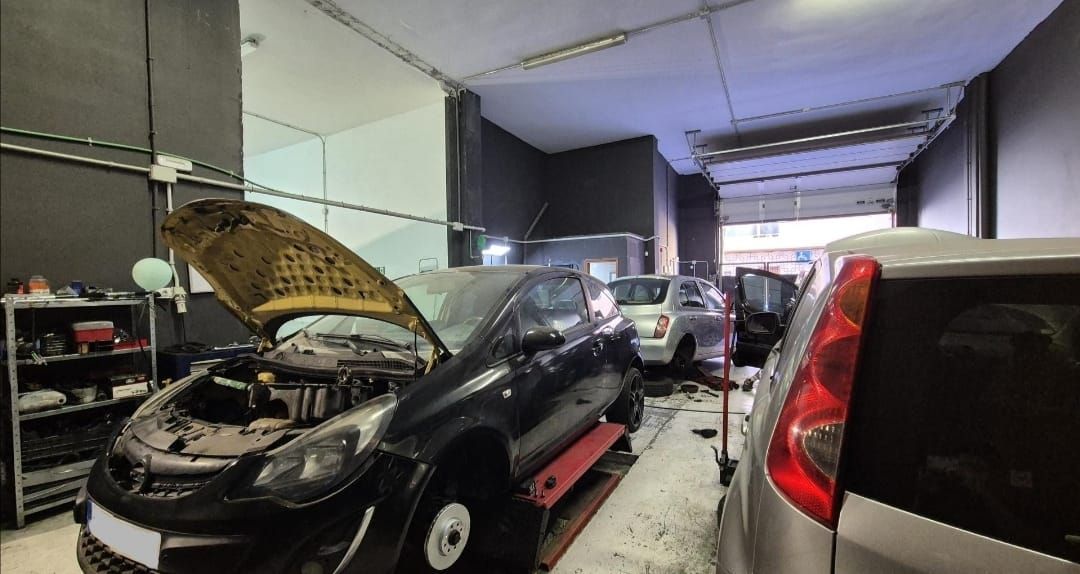Un taller mecánico con un coche negro en un elevador