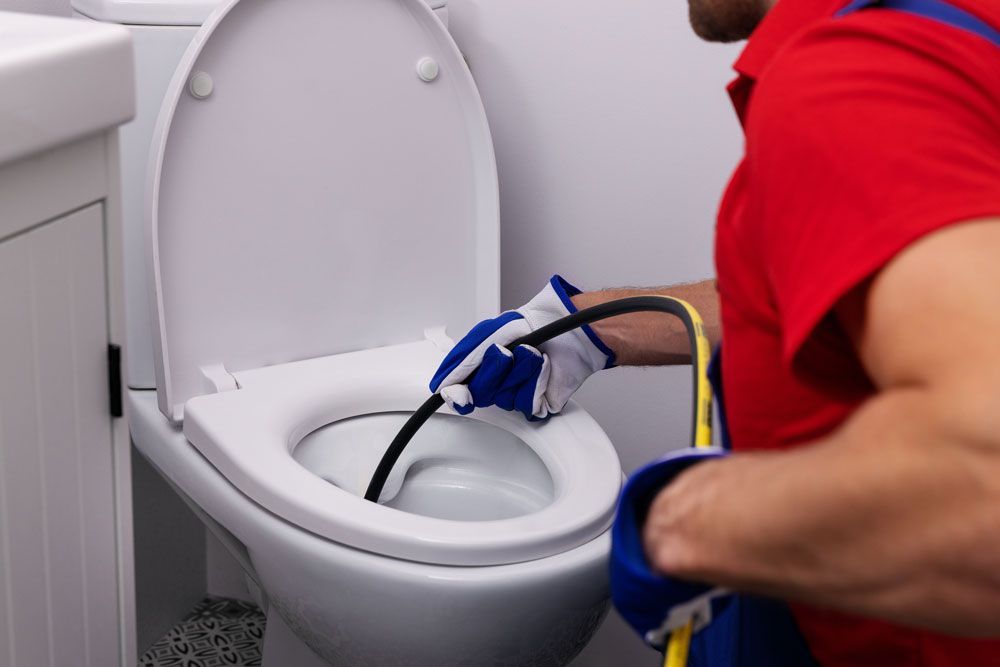 Rohrreinigung in Varel und Edewecht: Fachkraft beseitigt eine WC-Verstopfung mit einer Rohrreinigungsspirale.
