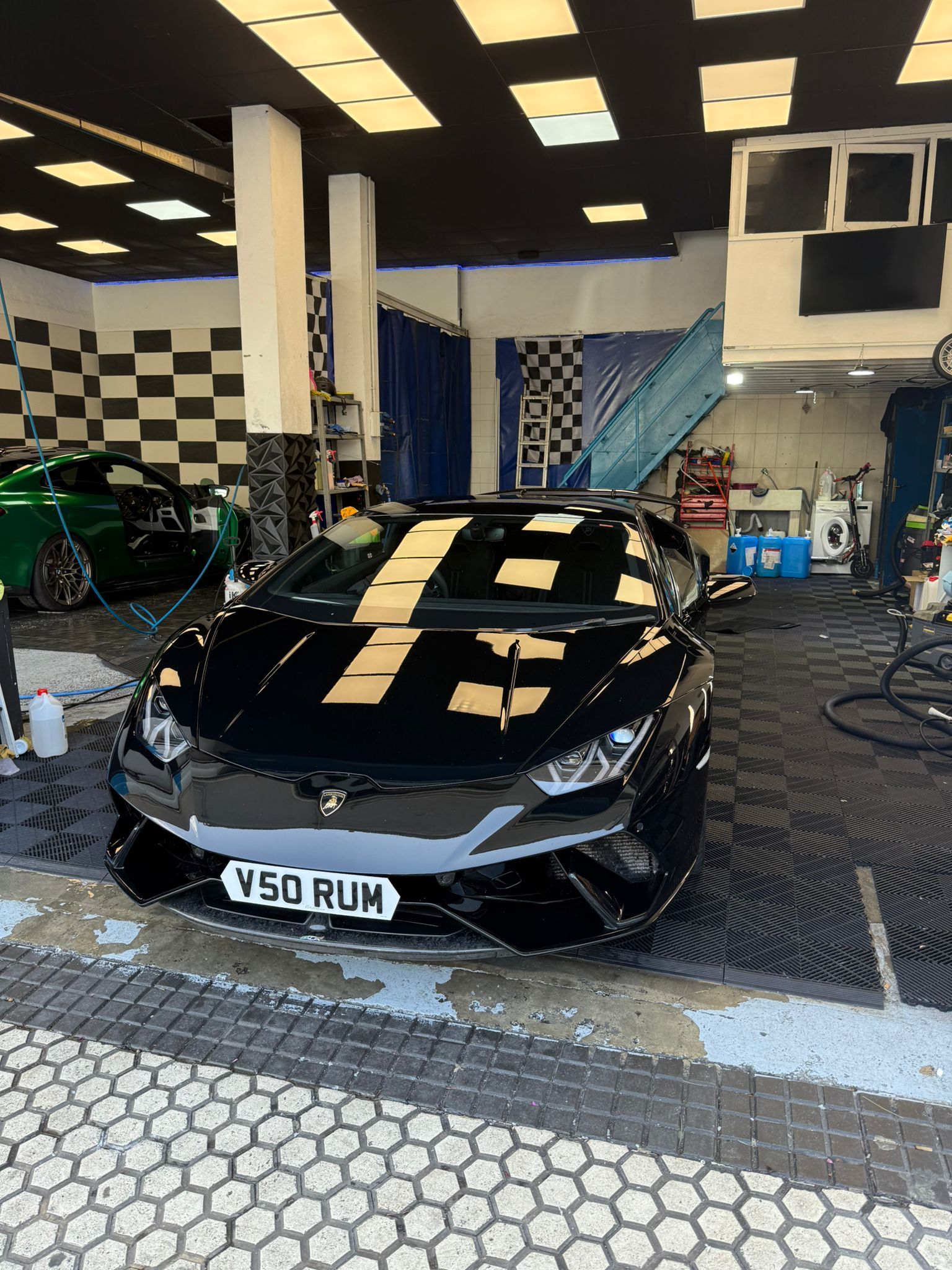 Asiento trasero de un coche negro con cinturón de seguridad y tela gris. La puerta está abierta y se ve el cielo azul.