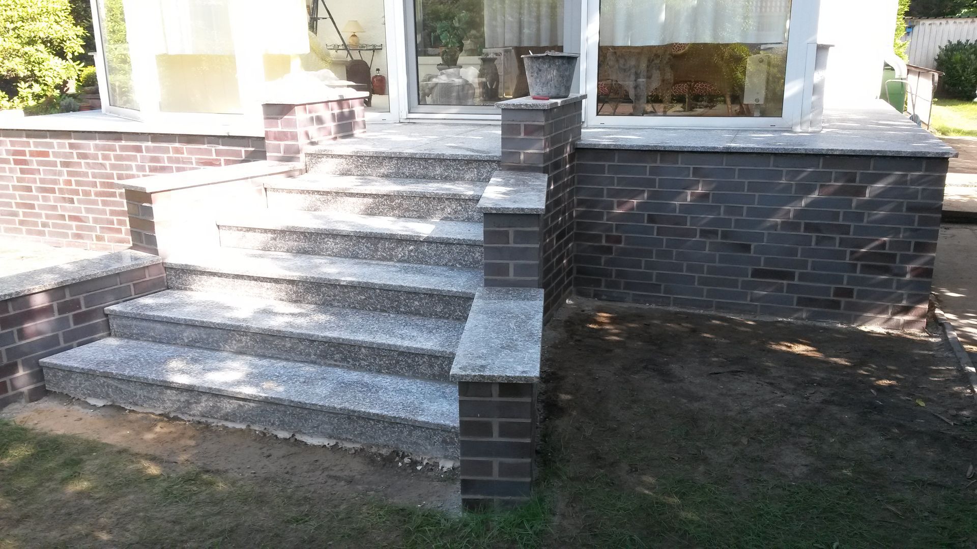 Eine Marmortreppe führt zu einem von Backsteinmauern umgebenen Eingang.