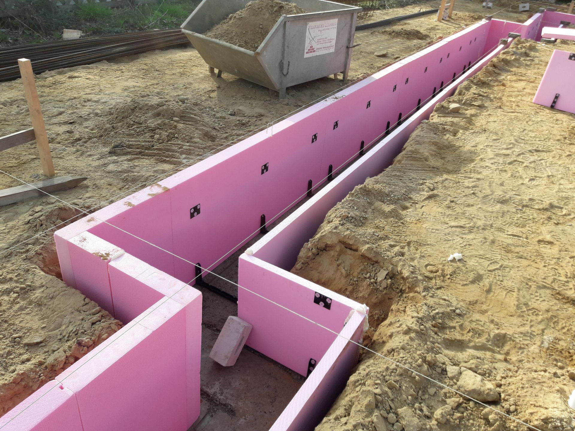 Eine Baustelle mit rosa Isolierschaumformen, die in einem Graben angeordnet sind.