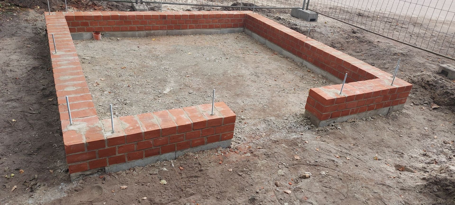 Ein rechteckiges Ziegelsteinfundament mit freiliegenden Bewehrungsstäben.