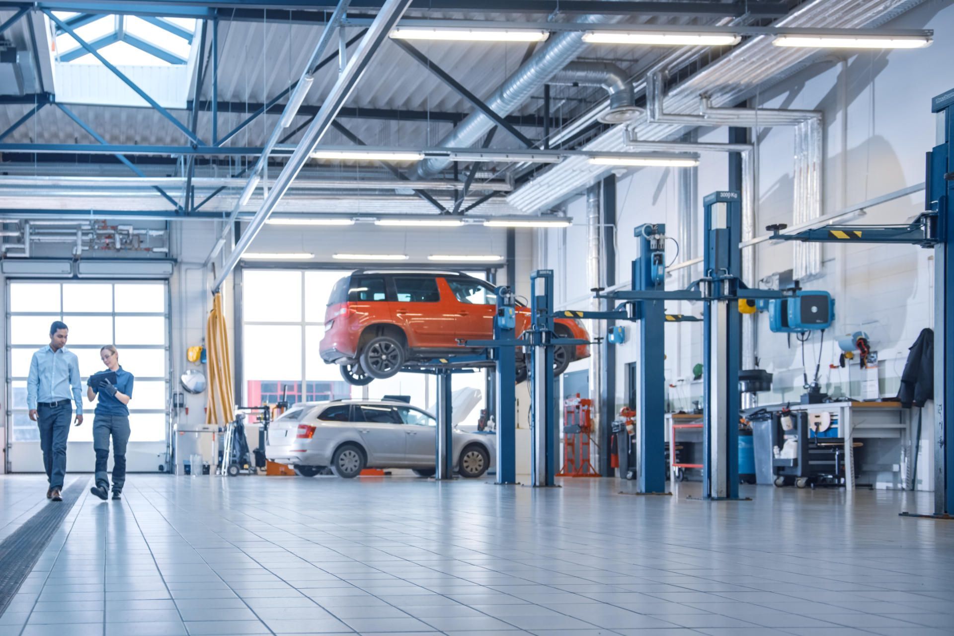 Ein Mechaniker spricht mit einem Kunden während das Auto auf der Hebebühne ist