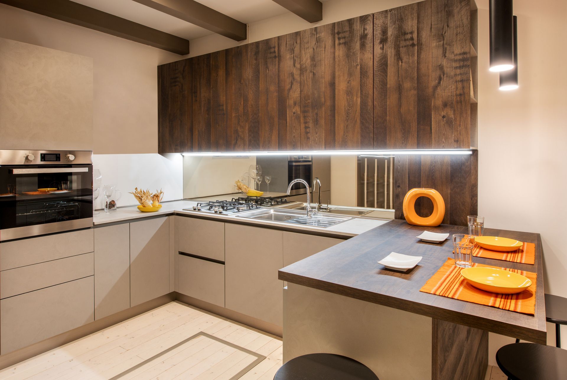 Cuisine moderne avec armoires gris clair, mur d'accent en bois et comptoir foncé.