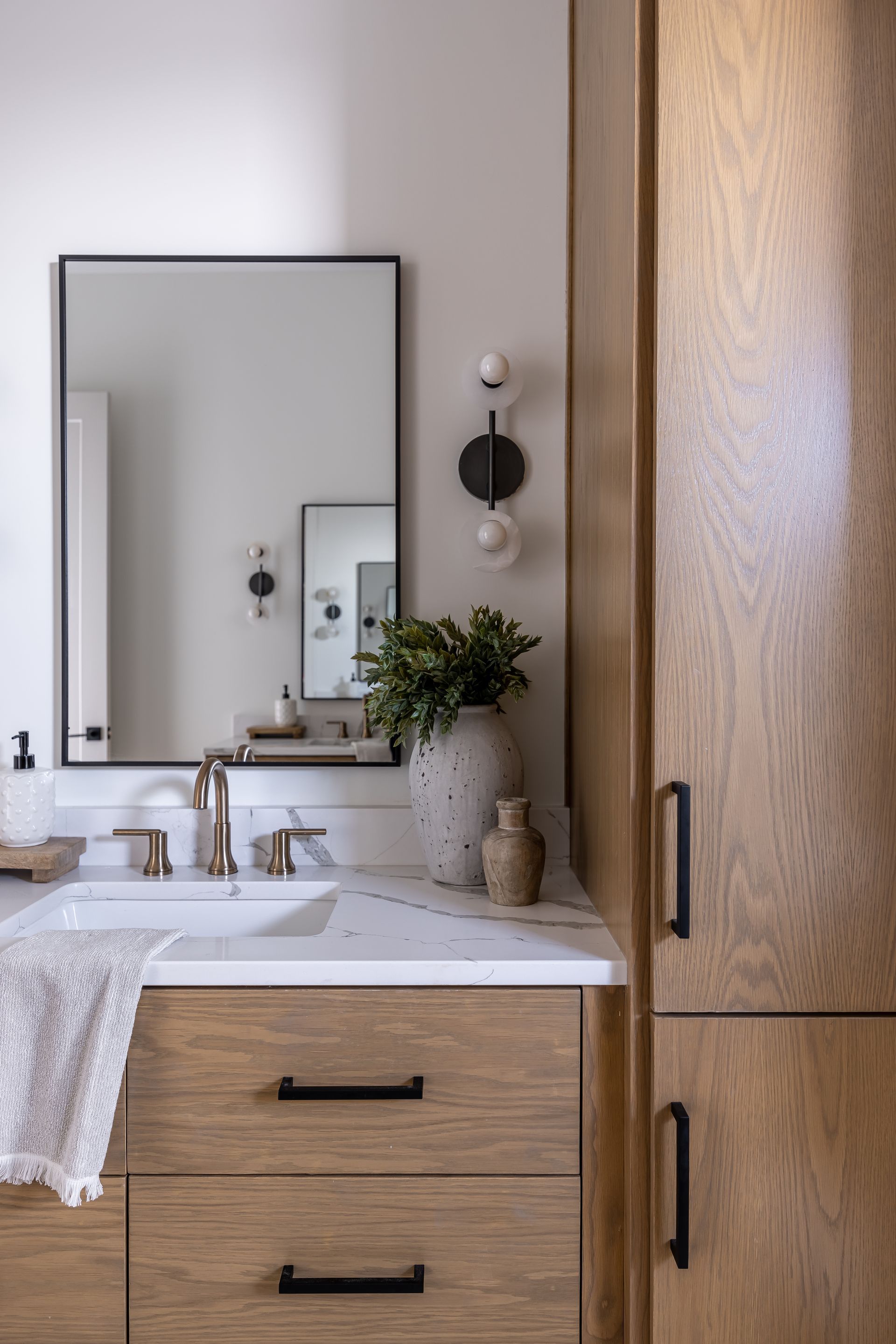 Meuble-lavabo de salle de bains avec armoire en bois, accents noirs et miroir rectangulaire.