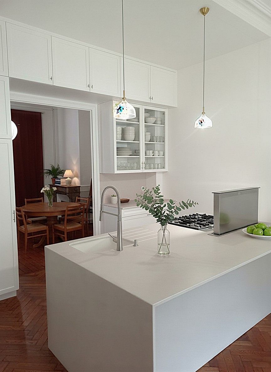 Armoires de cuisine vertes, dont une ouverte pour révéler des étagères coulissantes en fil de fer, contre un comptoir blanc.