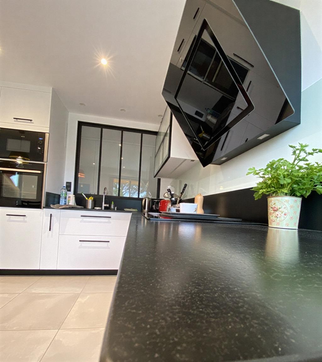 Comptoir de cuisine en bois avec armoires vert menthe, la lumière du soleil traversant une fenêtre.