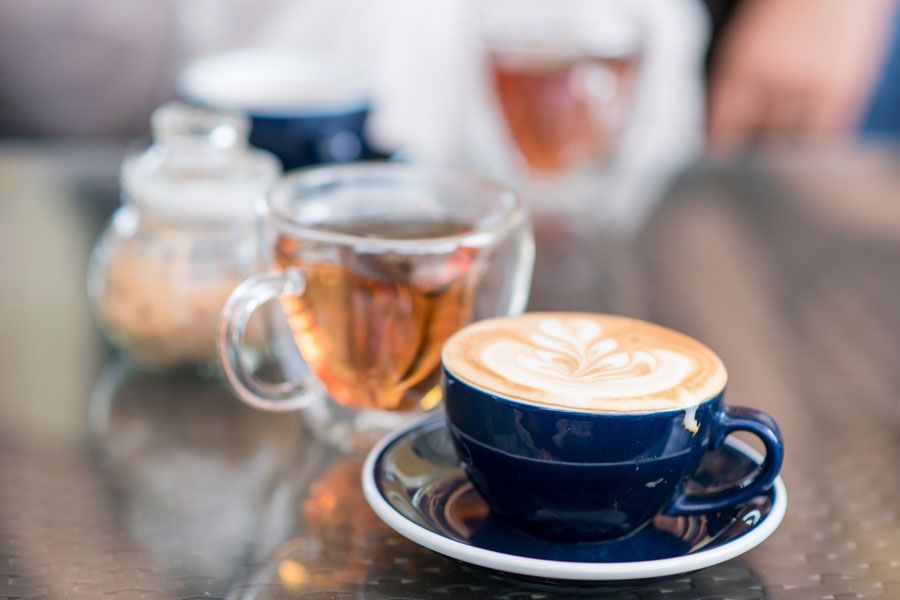 Una taza de café y una taza de té están sobre una mesa.