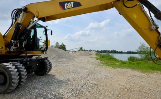 Gelber Bagger und im Hintergrund ein Kieselsteinweg