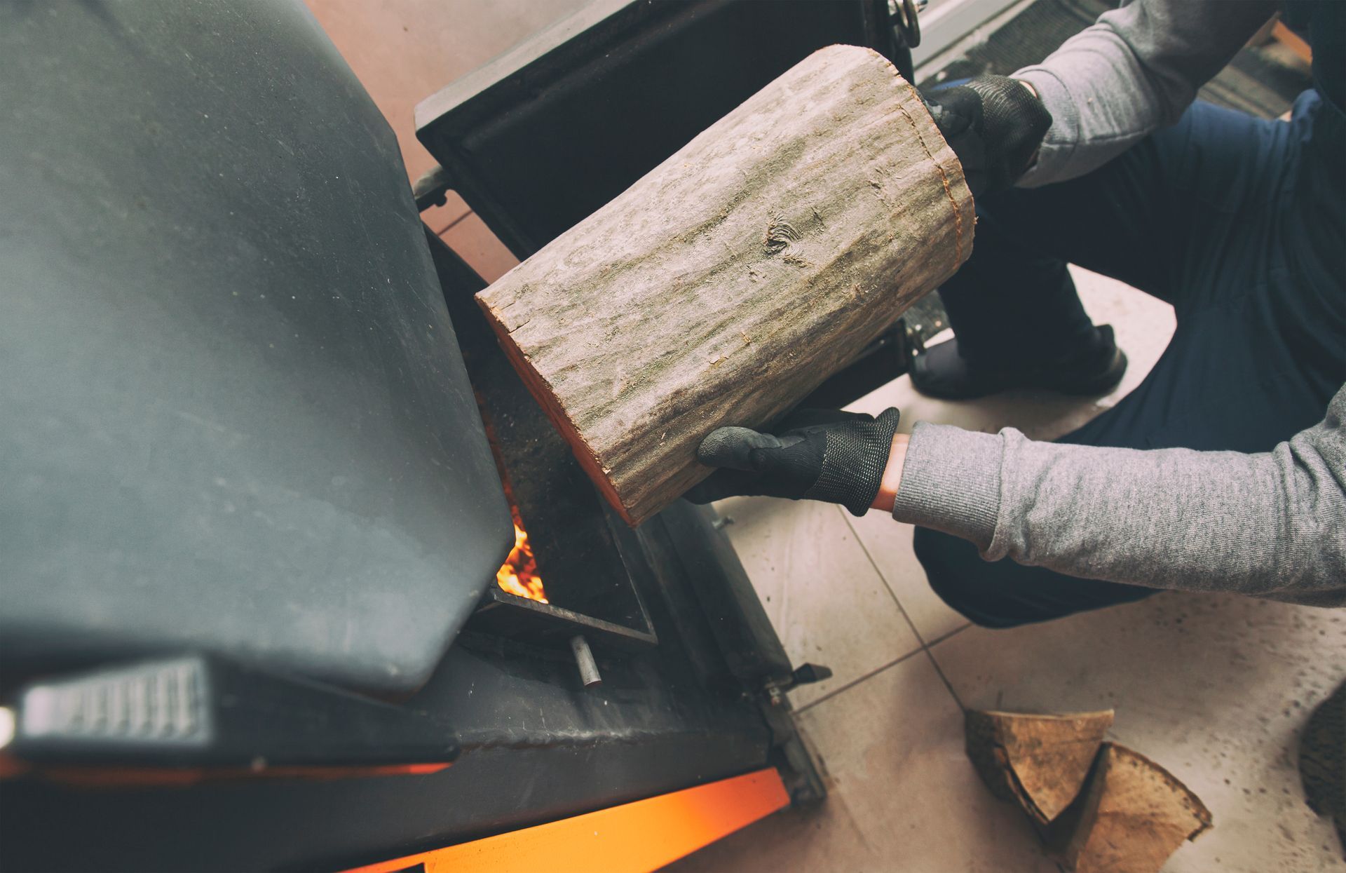 Homme qui met une bûche dans une chaudière à bois