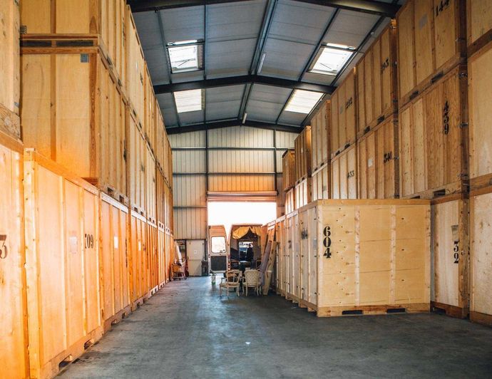 Des rangées de conteneurs de stockage en bois dans un entrepôt, une porte ouverte au bout.