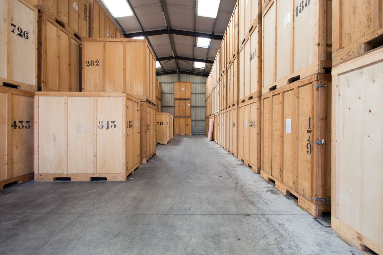 Unités de stockage dans un entrepôt ; des conteneurs en bois bordent les deux côtés d'une allée étroite.