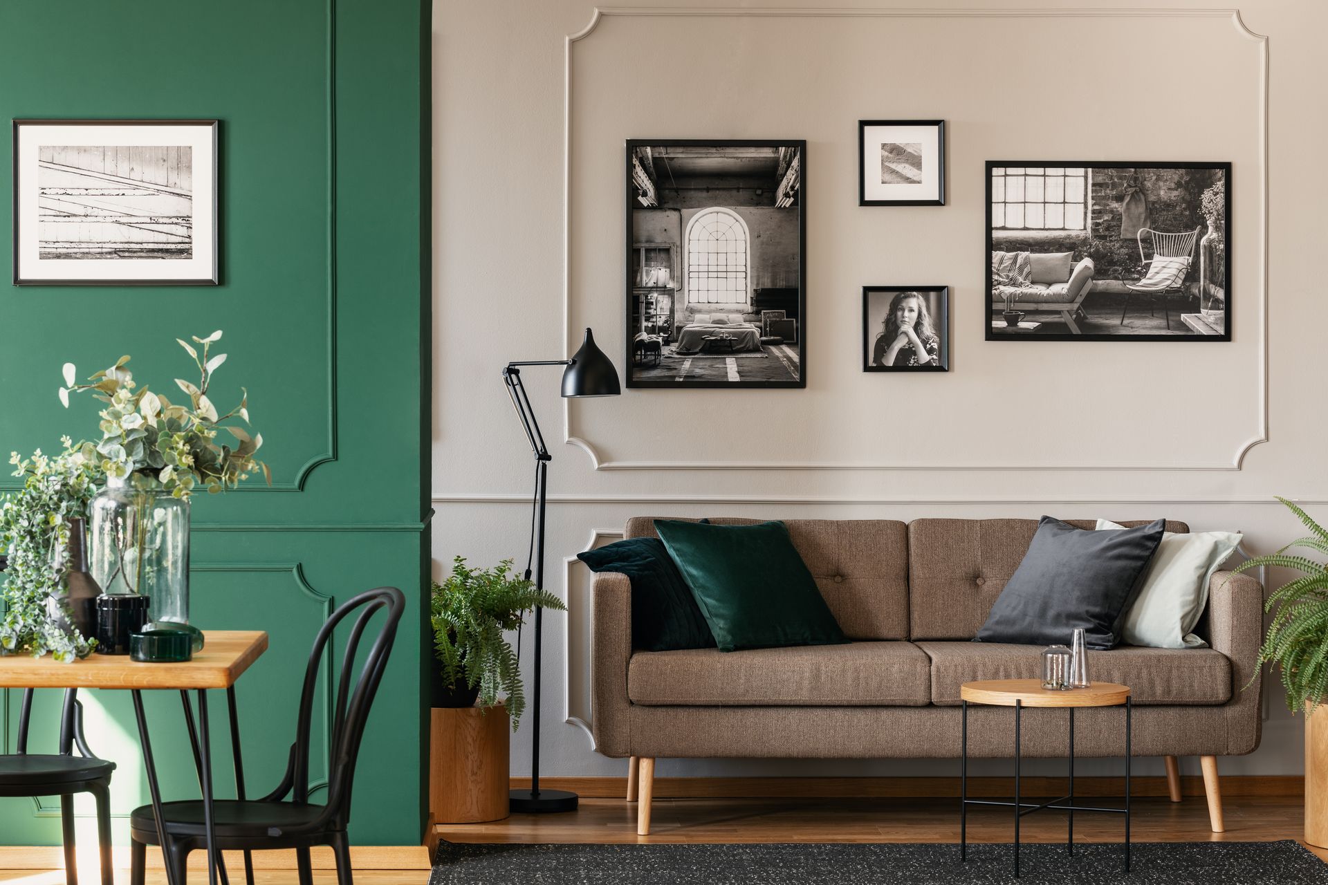 Salon avec un mur où sont accrochées des photos encadrées en noir et blanc.