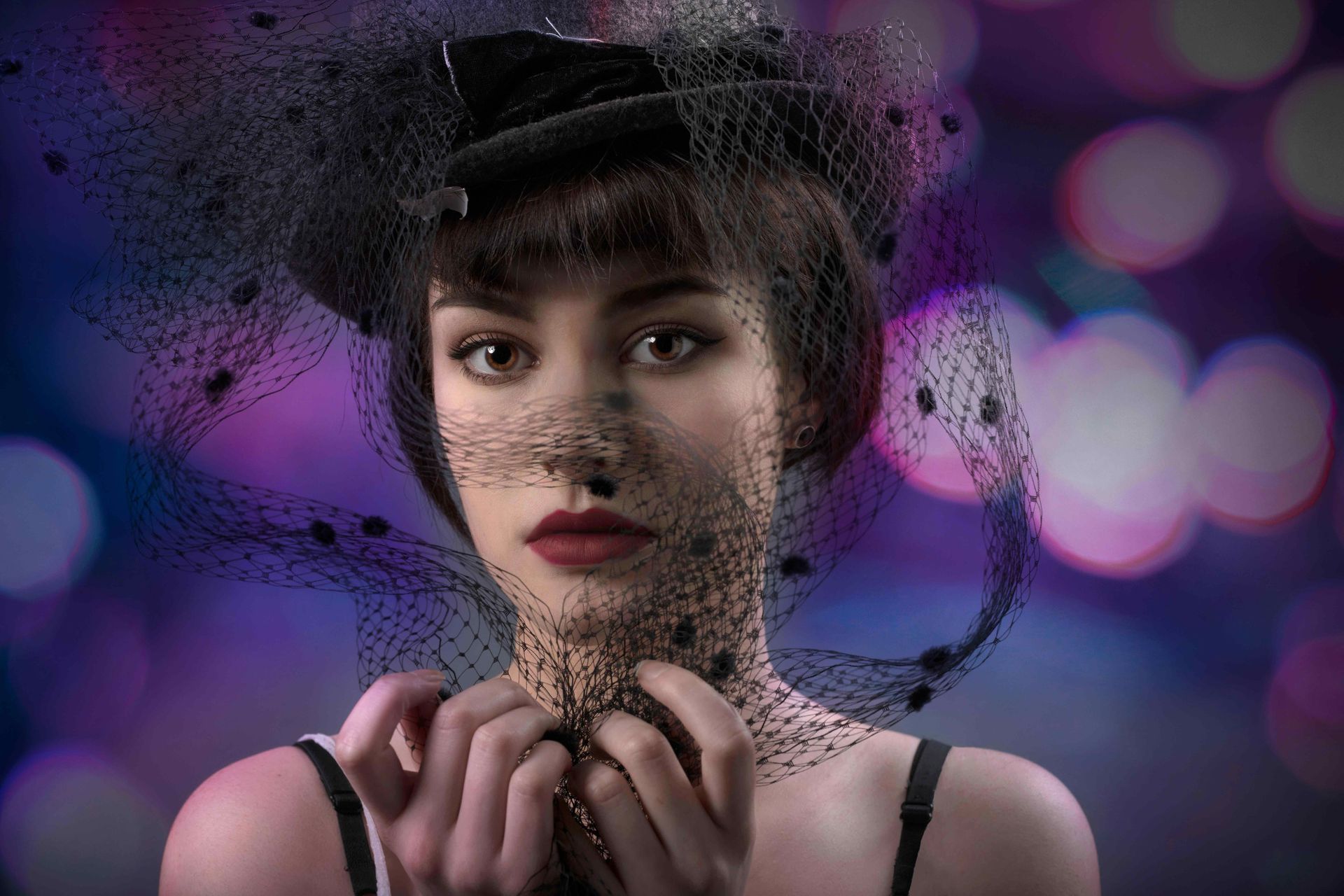 Portrait d'une femme portant un voile et chapeau noirs et du rouge à lèvres rouge.