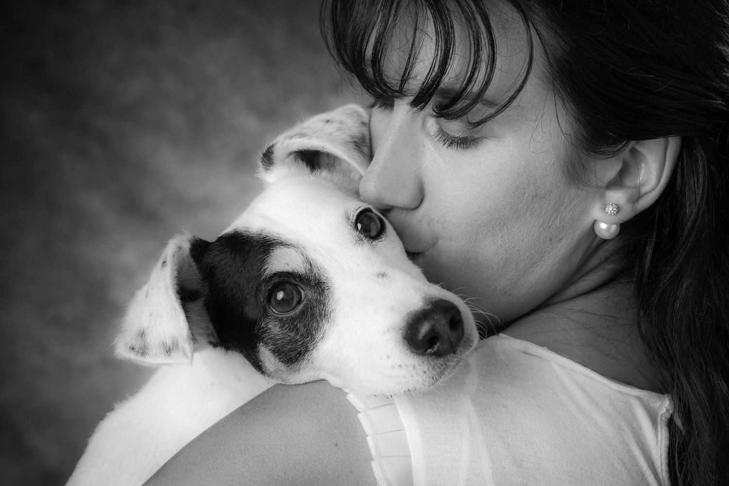 Photo en noir et blanc d'une femme qui embrasse un petit chien.