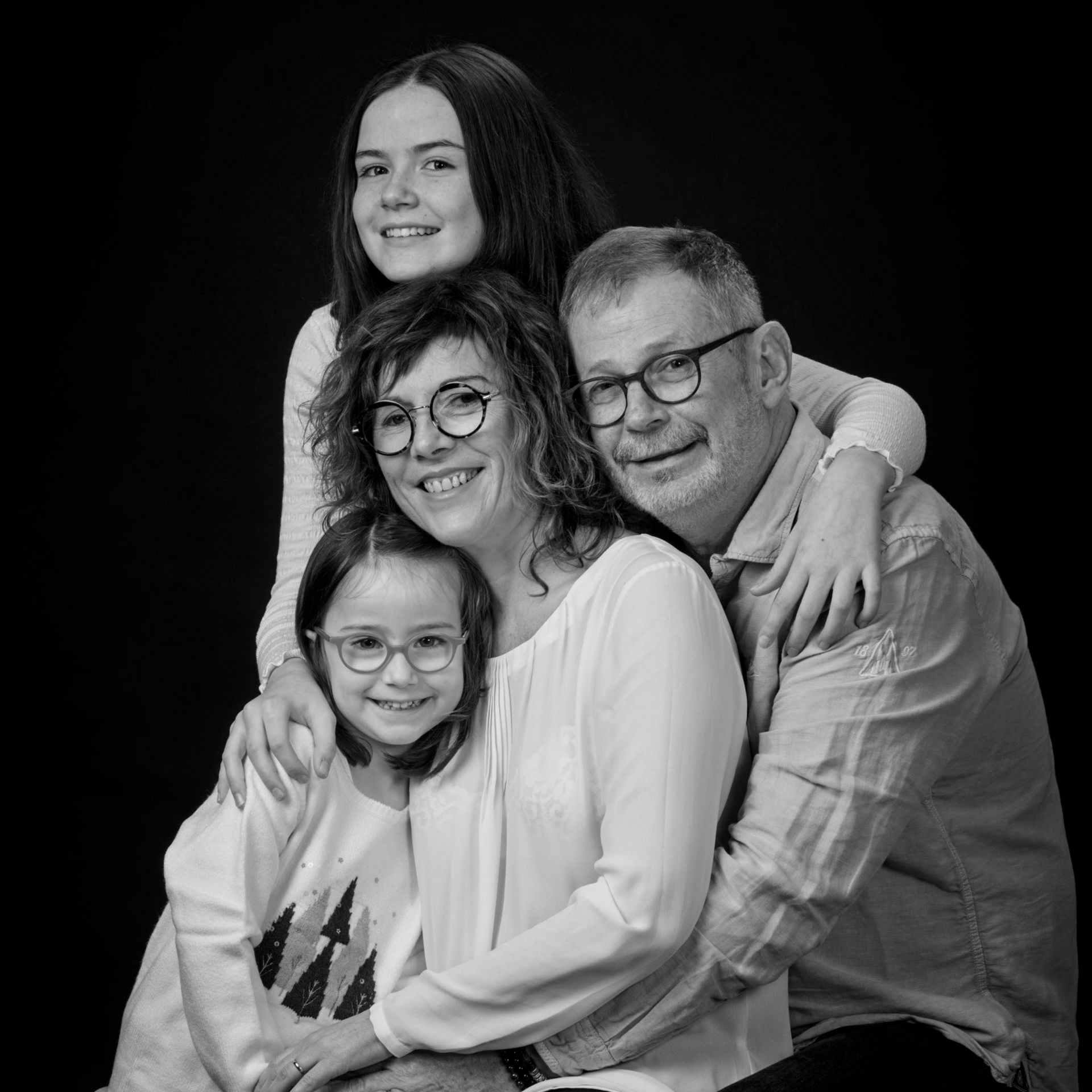 Portrait de famille en noir et blanc de deux parents et deux filles.