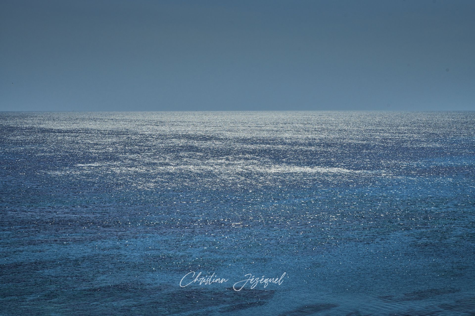 L'océan scintillant sous un ciel clair et lumineux.