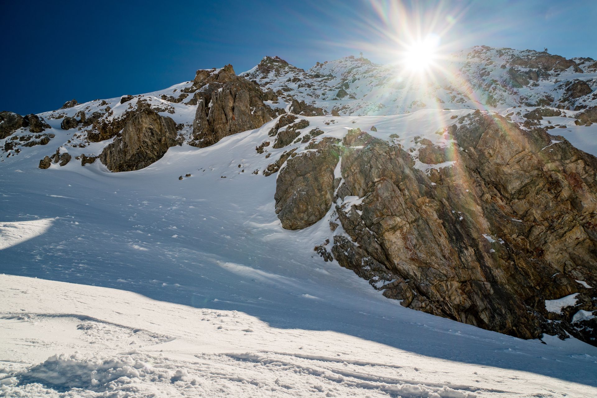 Eine Person in einer gelben Jacke steht vor einem schneebedeckten Berg