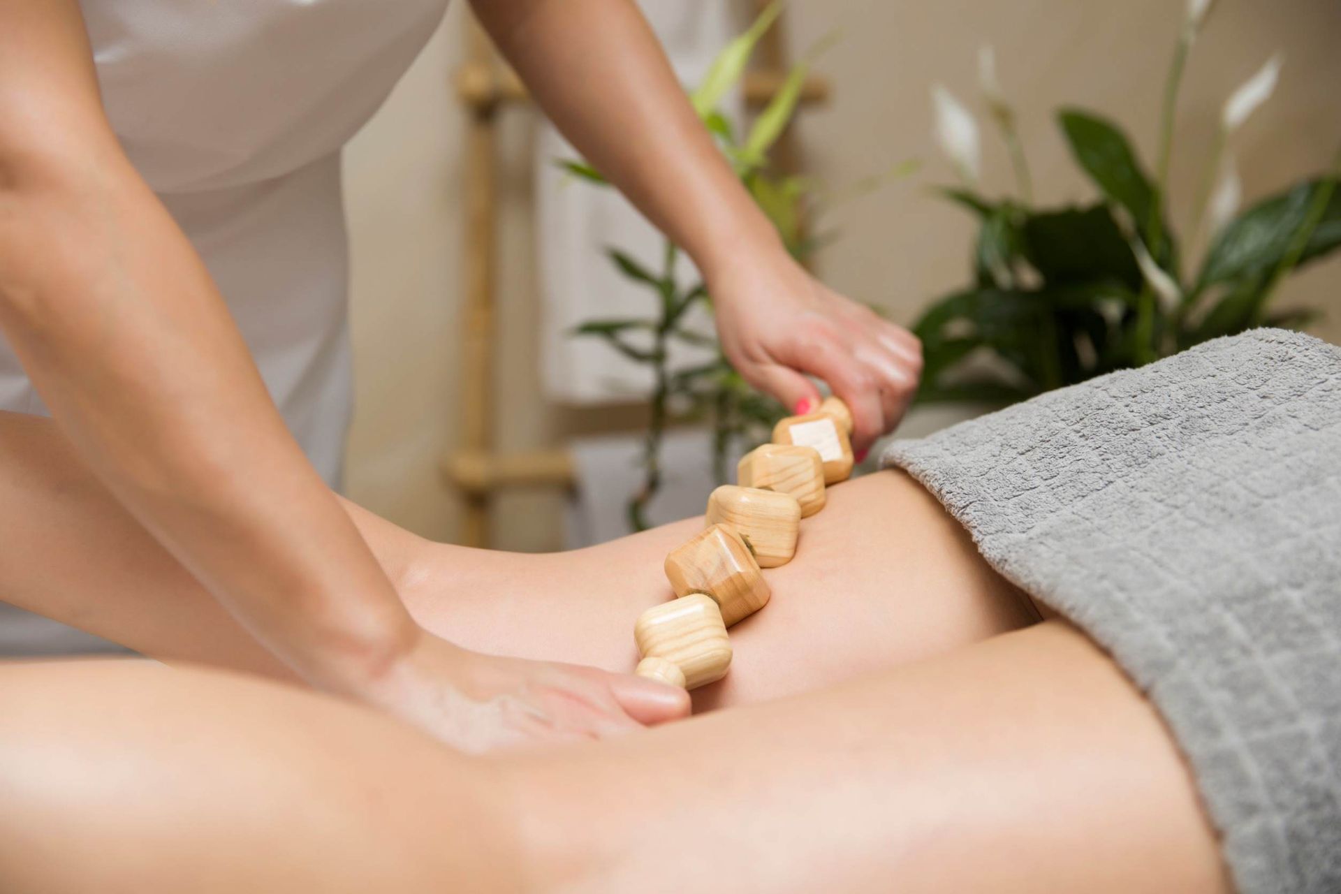 Una mujer está recibiendo un masaje con palos de madera en un spa.