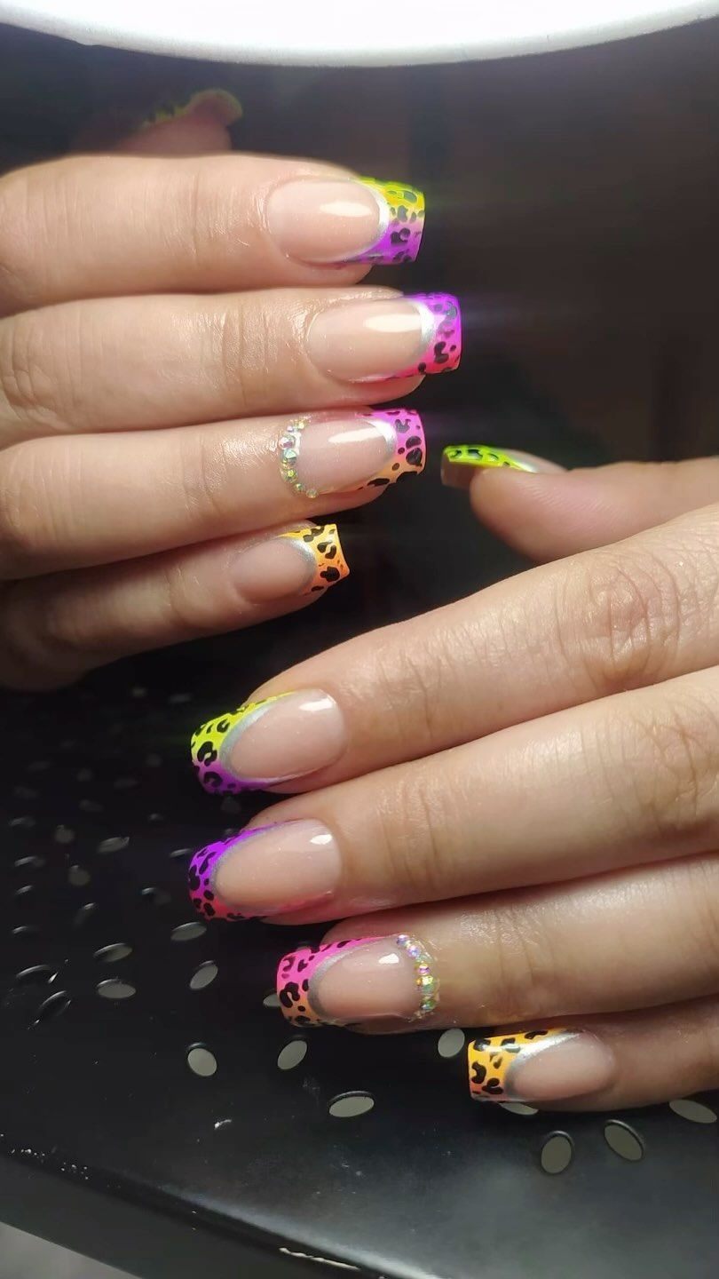 Un primer plano de las uñas de una persona con una manicura francesa neón.