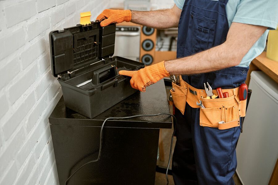 Un hombre está trabajando en un refrigerador con una caja de herramientas.