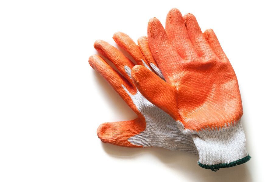 Un par de guantes naranjas y blancos sobre una superficie blanca.