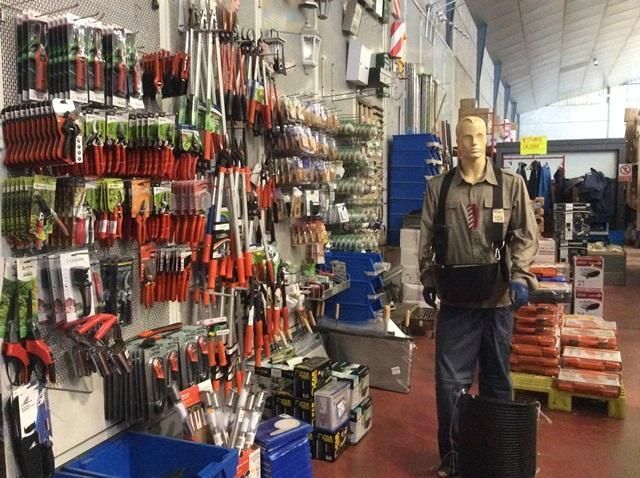 Un hombre está parado frente a una pared de herramientas en una tienda.
