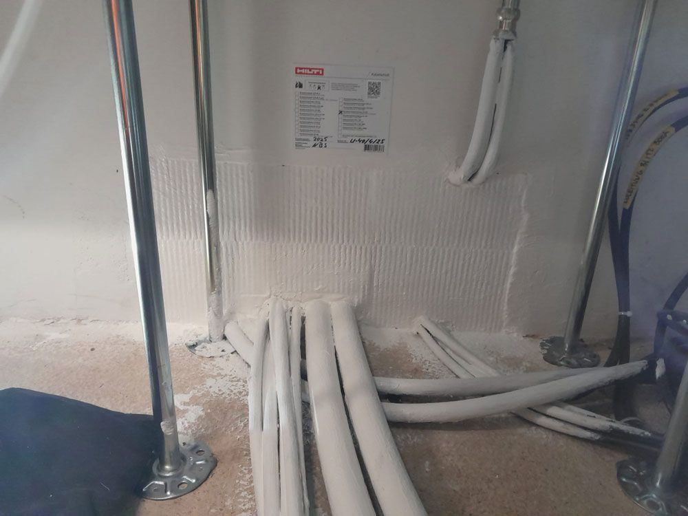 Rohre und Metallstangen vor einer strukturierten weißen Wand. In der Nähe der Basis ist weißer Klebstoff sichtbar.