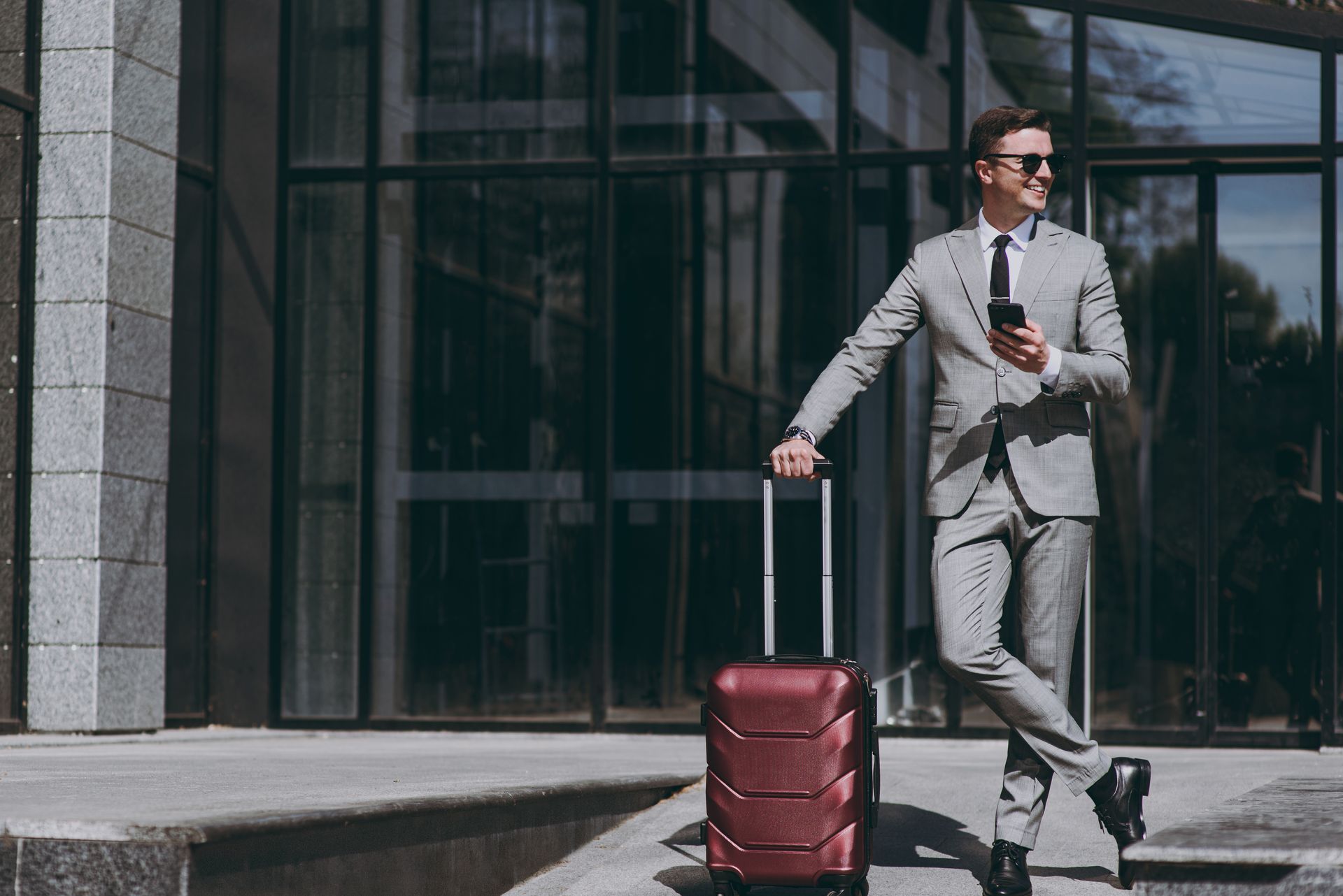 Un homme en costume avec une valise rouge attend son taxi
