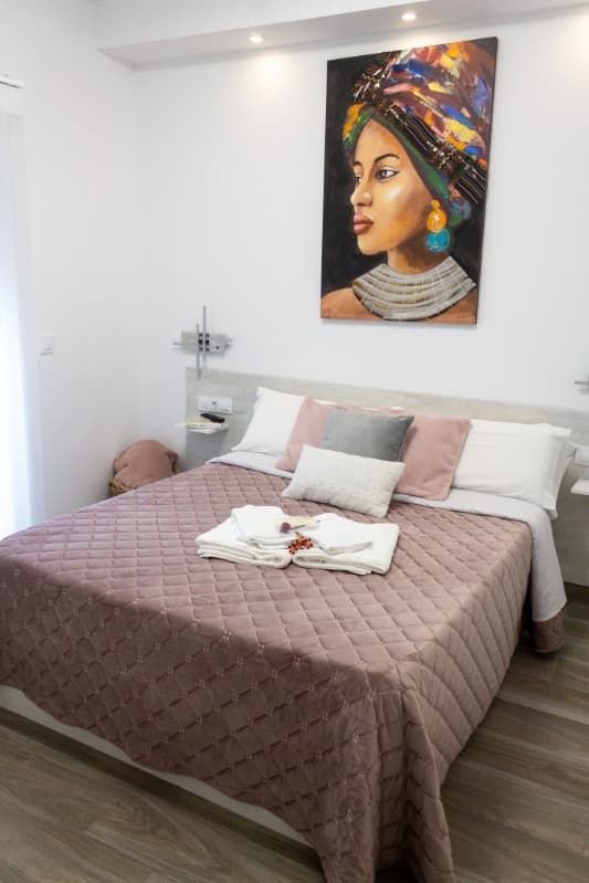 Hay un cuadro de una mujer en la pared encima de la cama.