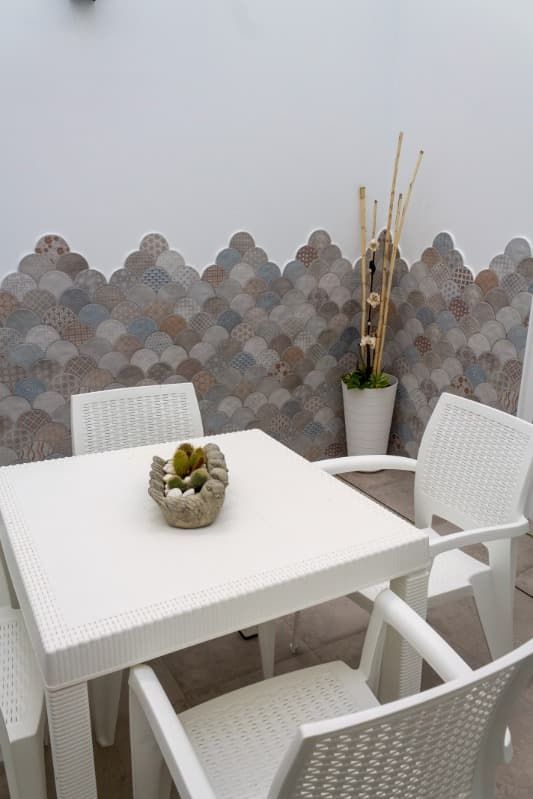 Una mesa blanca y sillas con un bol de fruta encima.