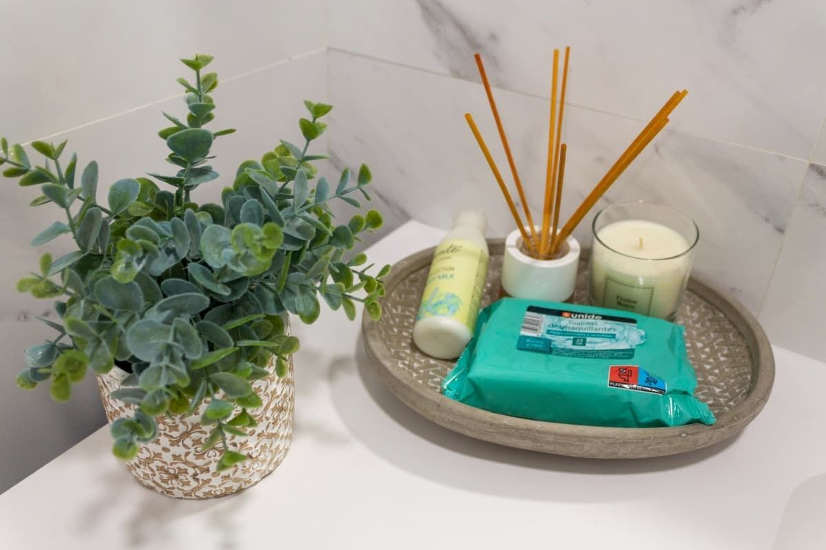 Un mostrador de baño con una planta, toallitas, velas y difusores de varillas.