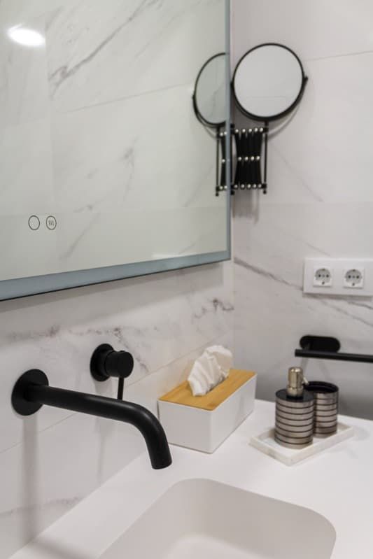 Un baño con lavabo, espejo y caja de pañuelos.