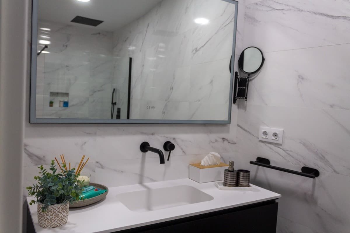 Un baño con lavabo, espejo y ducha.