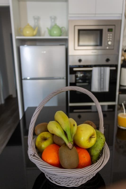 Una cesta de fruta reposa sobre un mostrador en una cocina.