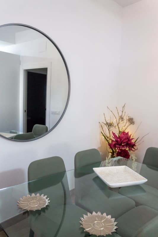 Un espejo redondo está colgado en una pared blanca en un comedor.