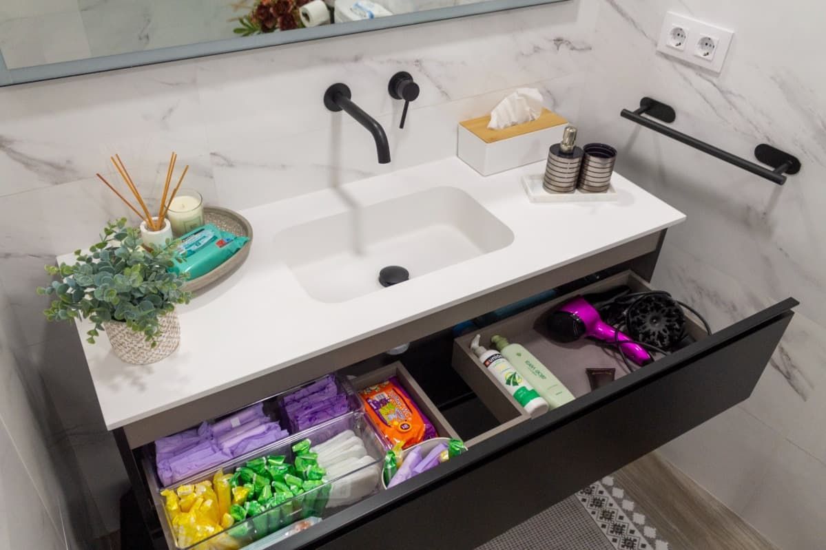 Un baño con lavabo, espejo y cajones abiertos.