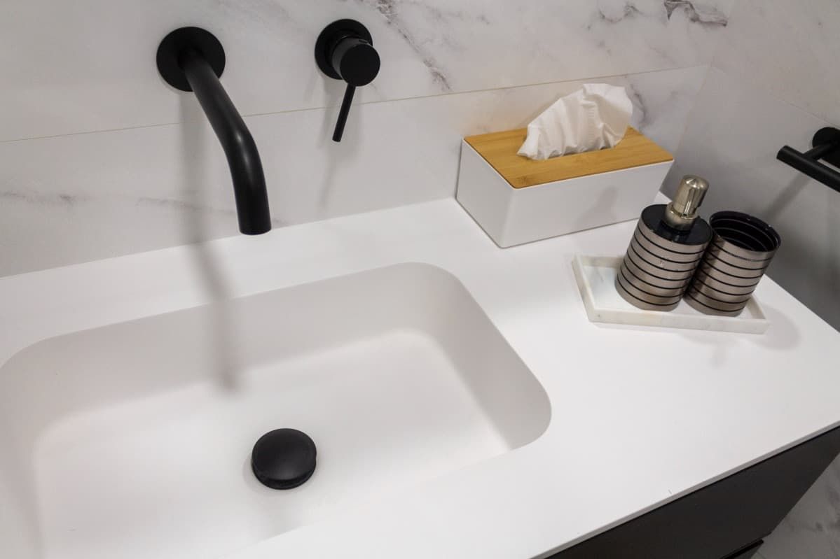 Un lavabo de baño con un grifo negro y una caja de pañuelos.