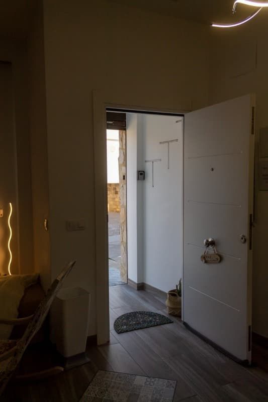 Una puerta blanca está abierta en un pasillo oscuro.