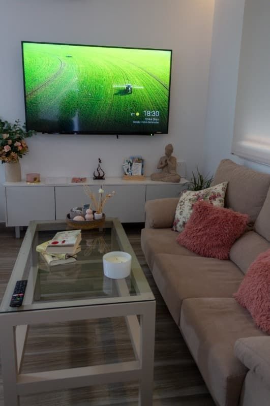 Una sala de estar con sofá, mesa de café y televisor de pantalla plana.