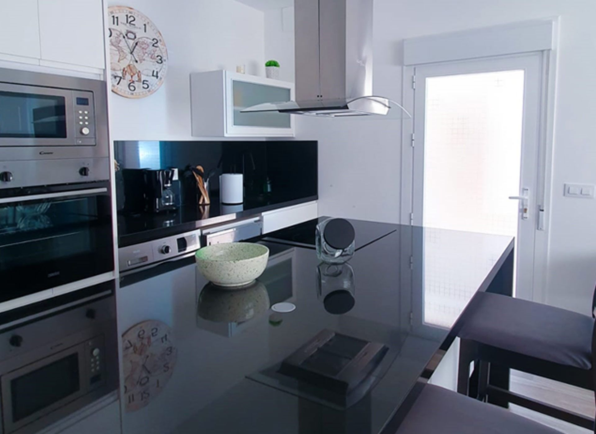 Una cocina con electrodomésticos de acero inoxidable y un reloj en la pared.