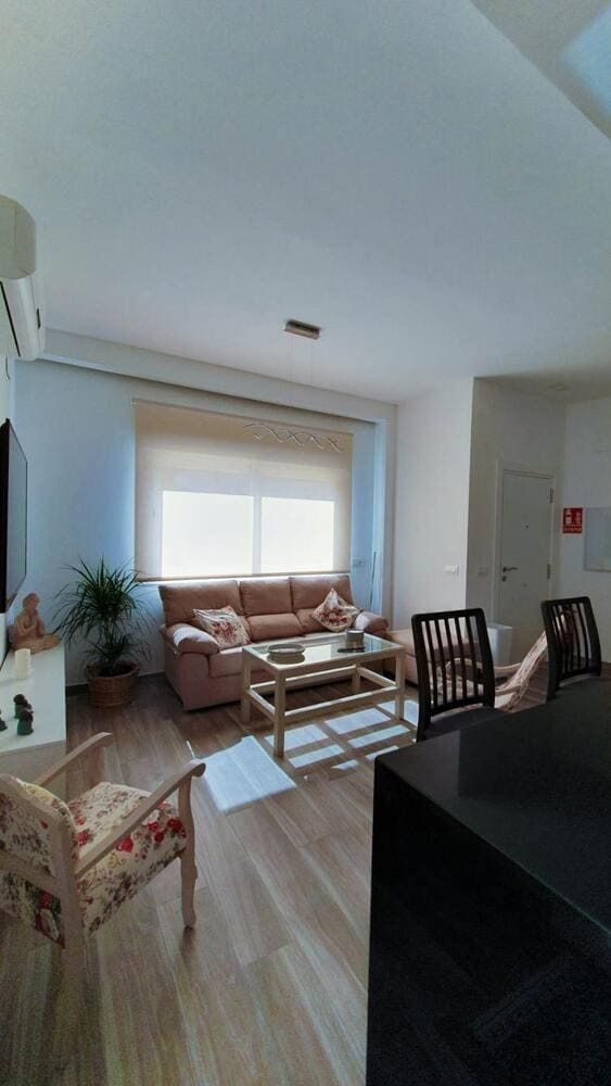 Una sala de estar con sofá, sillas, mesa de café y televisión.