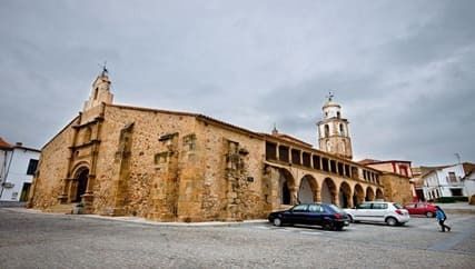 Un gran edificio de piedra con coches aparcados delante.