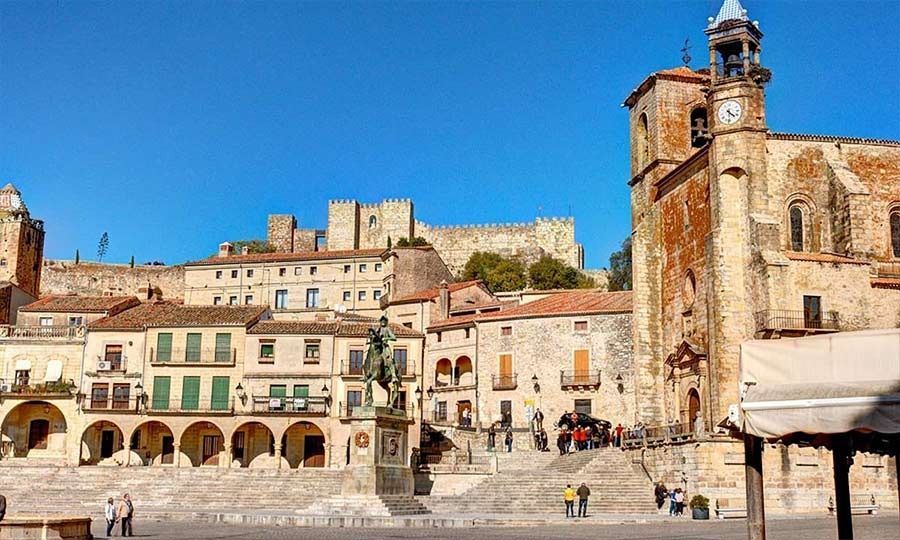 Una torre de reloj en el centro de una ciudad con un castillo al fondo.