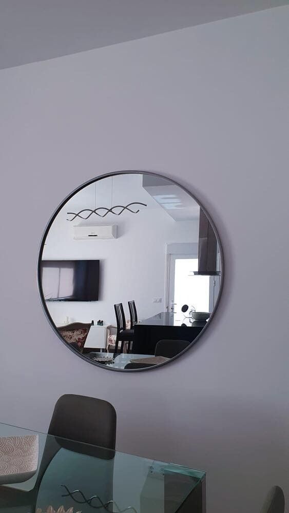 Un espejo redondo está colgado en una pared blanca en un comedor.