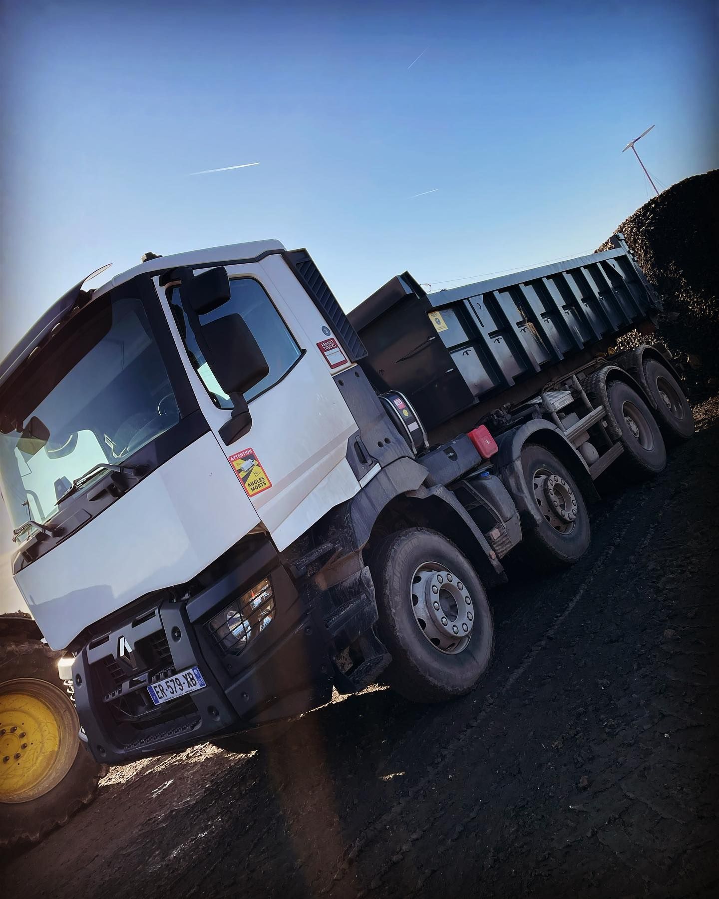 Camion-benne blanc à plateau surélevé.