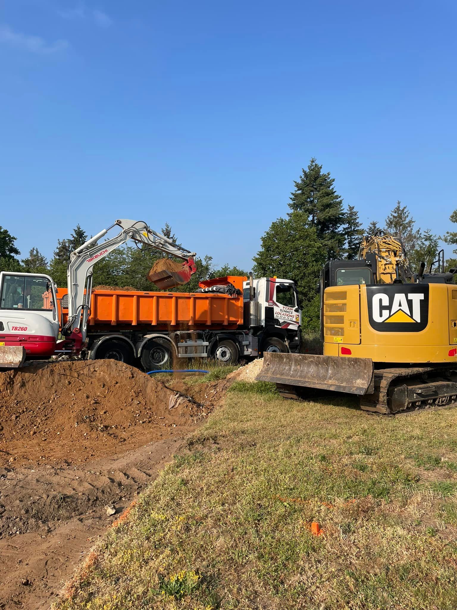 Chantier de construction : une pelle mécanique charge un camion-benne.